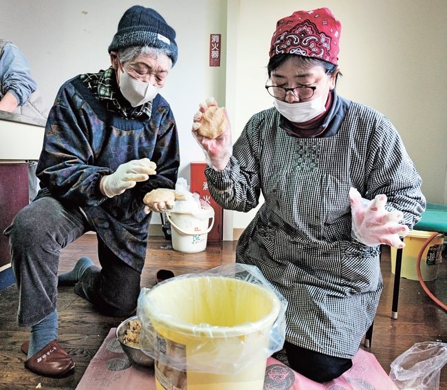材料を投げつけながら容器に詰める参加者＝島根県川本町川下、さつき会館