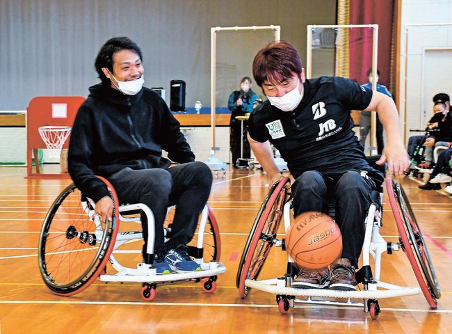 華麗に車いすを操る根木慎志さん（右）＝松江市東生馬町、松江清心養護学校