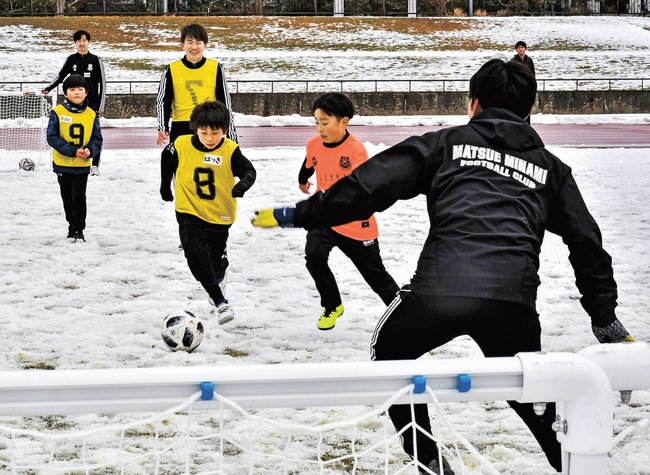 雪が積もる芝生の上でサッカーのミニゲームを楽しむ子どもたち=松江市上乃木10丁目、市営陸上競技場