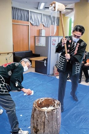 きねを振り上げて、餅をつく参加者＝松江市佐草町、敬仁会