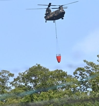 現場に散水する自衛隊の大型ヘリ＝６日午前１０時１４分、安来市広瀬町布部