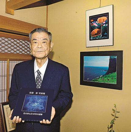 これまでのコンテスト入選作品と写真に収まる安達彰さん＝松江市浜乃木５丁目