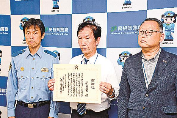 感謝状を受け取った足立勇二さん（中央）＝出雲市塩冶有原町２丁目、出雲署