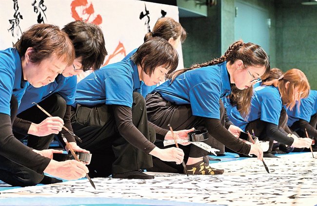 真剣な表情で揮毫する五風会の会員ら=浜田市黒川町、石央文化ホール