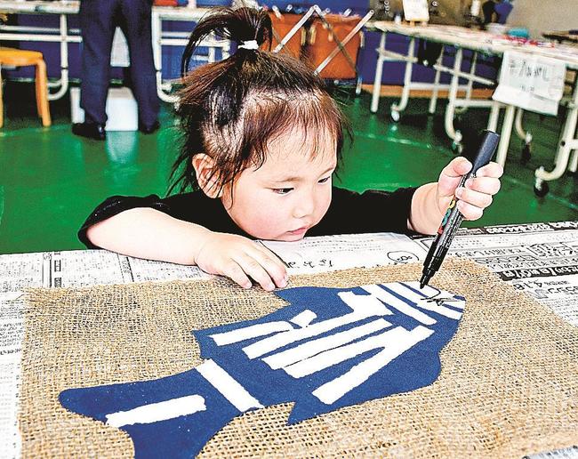 完成したこいのぼりに目玉を描く子ども＝浜田市野原町、市世界こども美術館